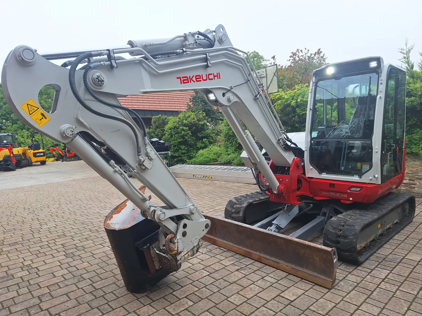 Midi bager Takeuchi TB370, bel z rdečimi elementi, na tlakovanem dvorišču